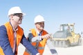 Supervisor explaining plan to colleague at construction site against clear sky Royalty Free Stock Photo