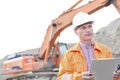 Supervisor looking away while holding clipboard at construction site Royalty Free Stock Photo