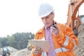 Supervisor reading clipboard while using walkie-talkie at construction site Royalty Free Stock Photo