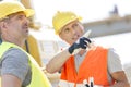 Supervisor showing something to colleague at construction site on sunny day