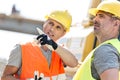 Supervisor showing something to colleague at construction site on sunny day