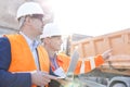 Supervisor showing something to colleague holding laptop at construction site