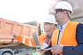 Supervisor showing something to colleague holding laptop at construction site