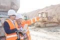 Supervisor showing something to coworker holding laptop at construction site