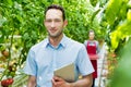 Full length view of Supervisor standing while holding digital tablet in greenhouse