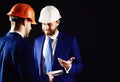 Supervisor and technician in helmets. Building inspector with smiling face talks to architect. Construction and happy Royalty Free Stock Photo