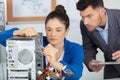 supervisor watching young female apprentice working on computer