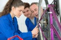 Supervisor watching young female mechanic tightening bolt