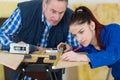 Supervisor watching young lady use tape measure