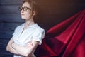 Superwoman office worker standing in a suit and red cloak