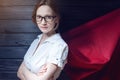 Superwoman office worker standing in a suit and red cloak