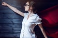 Superwoman office worker standing in a suit and red cloak