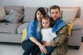 Supoort Ukraine conception. Soldier in uniform is at home with his wife and daughter Royalty Free Stock Photo