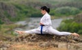 Supple young woman doing the splits on a rock