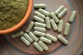 Supplement kratom green capsules and powder on brown plate. Herb Royalty Free Stock Photo