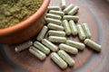 Supplement kratom green capsules and powder on brown plate. Herb Royalty Free Stock Photo