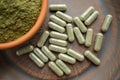 Supplement kratom green capsules and powder on brown plate. Herb Royalty Free Stock Photo