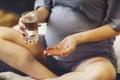 Pregnant woman taking prenatal vitamins during pregnancy, holding water glass and pill in her hands Royalty Free Stock Photo