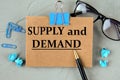 SUPPLY and DEMAND - words on brown paper on the background of glasses, pens and paper clips Royalty Free Stock Photo