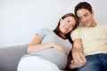 Support and anticipation. Happy young pregnant couple sitting on their couch at home relaxing. Royalty Free Stock Photo