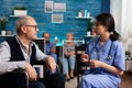 Support assistant worker explaining healthcare treatment to disabled senior man Royalty Free Stock Photo