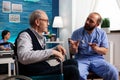 Support assistant worker explaining healthcare treatment to disabled senior man Royalty Free Stock Photo