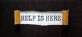 Support and help is here symbol. Words `help is here` appearing behind torn black paper. Beautiful black background. Business,