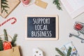 Support Local Business text written on blackboard. Flat lay with Support Local Business quote, Christmas decoration and Royalty Free Stock Photo