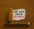 Support symbol. Words `we are here to help` appearing behind torn brown paper. Beautiful brown background. Wooden pencil. Busine