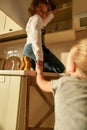 Support. Two naughty kids, brother and sister trying to find something sweet in the kitchen cupboard. Little girl