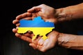 Support for Ukraine in the war with Russia. Hands holding the flag of Ukraine in the shape of the borders of Ukraine