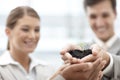 Supporting the future of their company. A group of businesspeople with their hands cupped around a small plant.