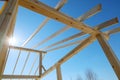 Supporting wooden structure for roof rafters, repeating beams on background of sky