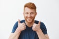 Supportive and attractive adult redhead male with bristle liking great plan raising hands, showing thumbs up, smiling
