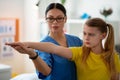 Supportive beaming dark-haired doctor gently holding her young patient