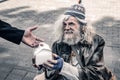 Dirty grey-haired senior homeless wearing ragged clothes and receiving food