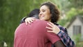 Supportive wife meeting husband in front of home and giving him welcome hug