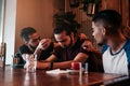 Supportive young men encourage their brokenhearted friend. Arabian guys cheer him up in restaurant. Friendship concept. Royalty Free Stock Photo