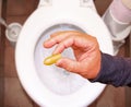 Suppository for constipation in the hand of an elderly person in the toilet against the background of the toilet bowl