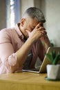 Suppressed project failure middle aged man covered his face with hands sitting at table with laptop at home. Freelancer