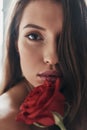 Supremely sensual. Attractive young woman holding a red rose and Royalty Free Stock Photo