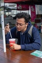 Photograph of a young man chilling and drinking fresh cold red beverage at park Royalty Free Stock Photo