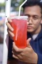 Photograph of a young man chilling and drinking fresh cold red beverage at park Royalty Free Stock Photo