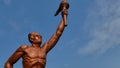 Surakarta, Indonesia, 20th June 2023, Statue of spirit of sport in a form of man holding torch against blue sky, Patung obor