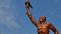 Surakarta, Indonesia, 20th June 2023, Statue of spirit of sport in a form of man holding torch against blue sky, Patung obor