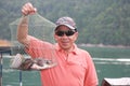 One of Asian tourists shows fish he caught from the Chao Lan Dam