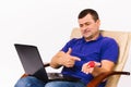 A surdomute man holds a hearing aid and a red heart in his hands while discuss by video communication via a laptop. Royalty Free Stock Photo