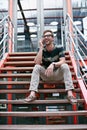 It sure feels good at the top. a handsome young man using his mobile phone while sitting on the steps of an office.