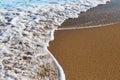 The surf as a natural background: a foamy wave on wet sea sand Royalty Free Stock Photo