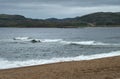 Surf on the coastline of the north sea with a mountainous coast in the background